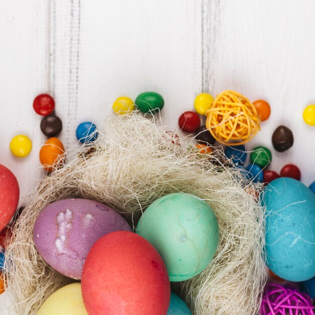 Huevos de Pascua en nido con caramelos en mesa