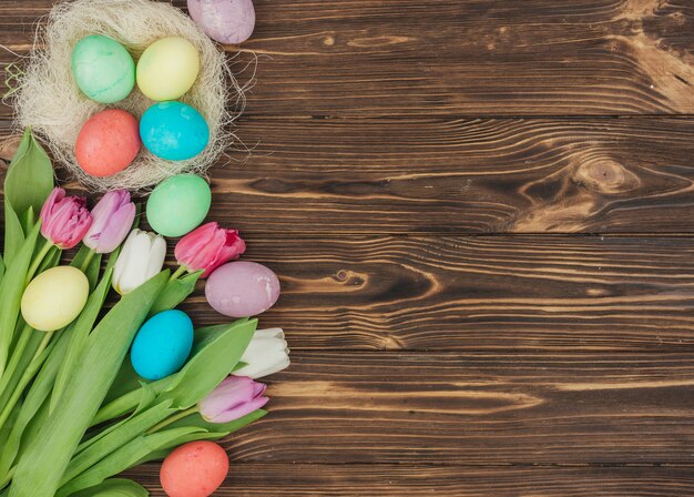 Huevos de Pascua en nido con tulipanes en mesa