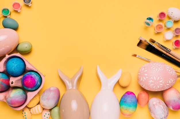 Huevos de Pascua con orejas de conejo y pinceles con espacio para escribir el texto