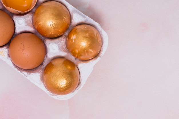 Huevos de Pascua de oro en rejilla en mesa rosa