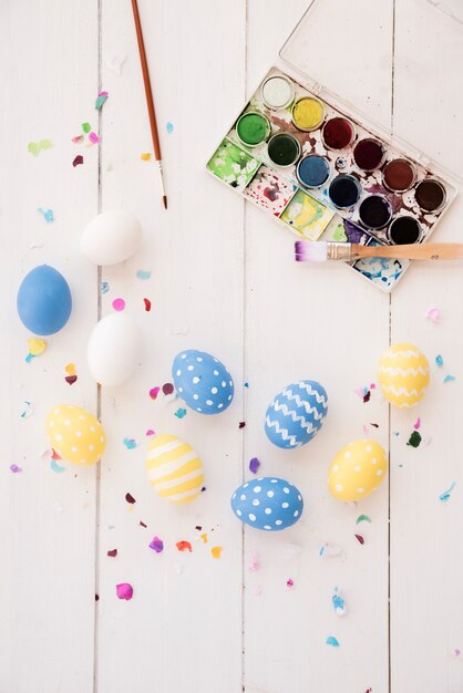 Huevos de Pascua con paleta de pintura y pinceles.