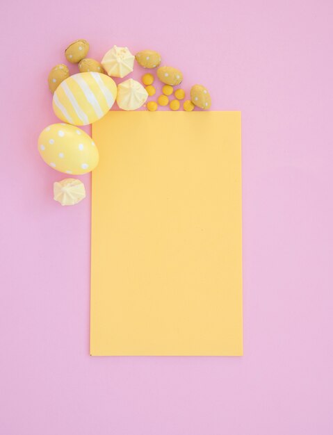 Huevos de Pascua con papel amarillo en blanco sobre mesa rosa