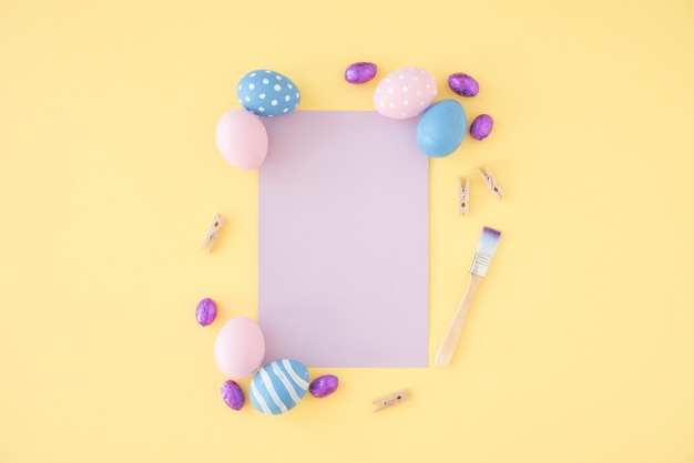 Foto gratuita huevos de pascua con papel morado en blanco sobre mesa