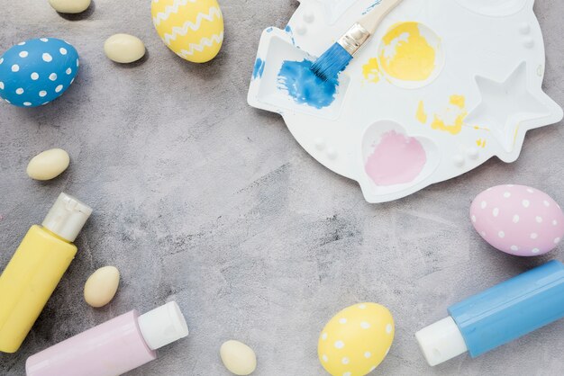 Huevos de Pascua con pegamento y paleta de pintura en mesa