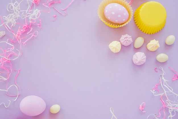 Huevos de Pascua con pequeños dulces en mesa morada