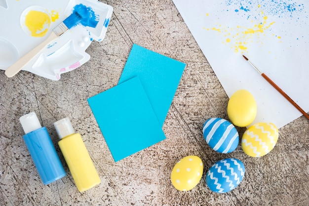 Huevos de Pascua con pequeños papeles y pegamento en la mesa