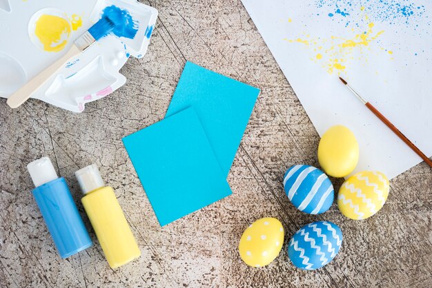 Huevos de Pascua con pequeños papeles y pegamento en la mesa