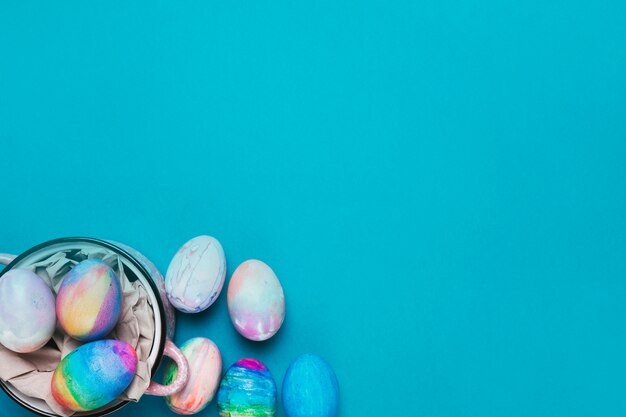 Huevos de Pascua pintados dentro de la olla en el fondo azul con espacio de copia para escribir el texto