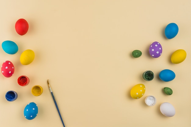 Huevos de Pascua con pinturas y pincel sobre mesa