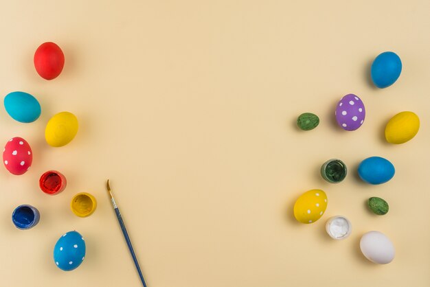 Huevos de Pascua con pinturas y pincel sobre mesa