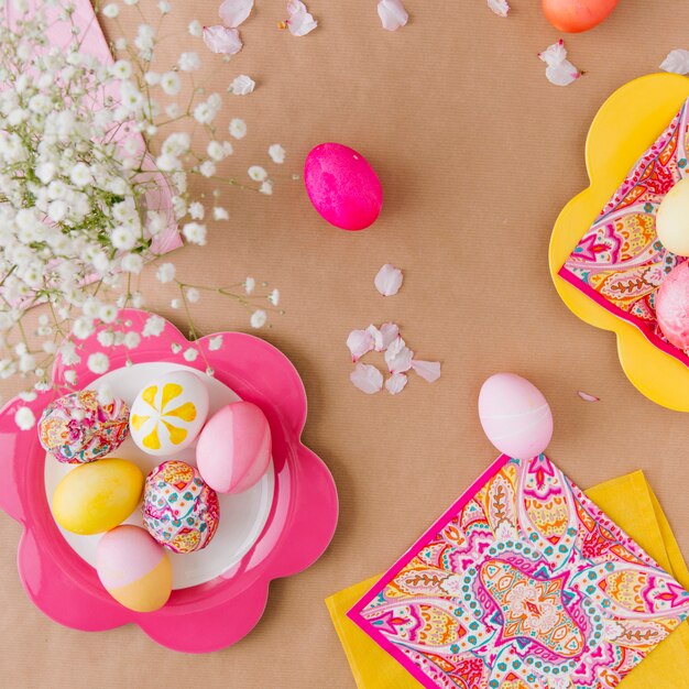 Huevos de Pascua en platos cerca de servilletas y flores