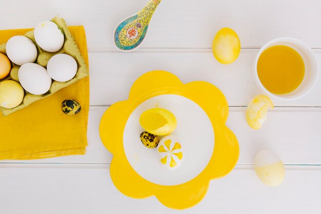 Huevos de Pascua en un recipiente cerca de un plato y una taza con líquido tinte