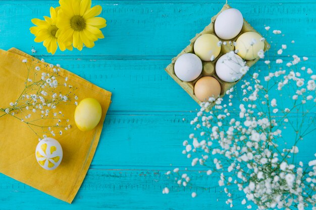 Huevos de Pascua en un recipiente cerca de ramitas de flores