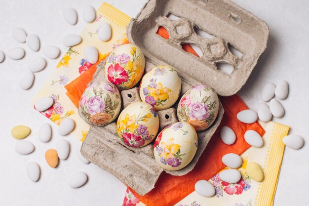 Huevos de Pascua en un recipiente cerca de servilletas y piedras pequeñas