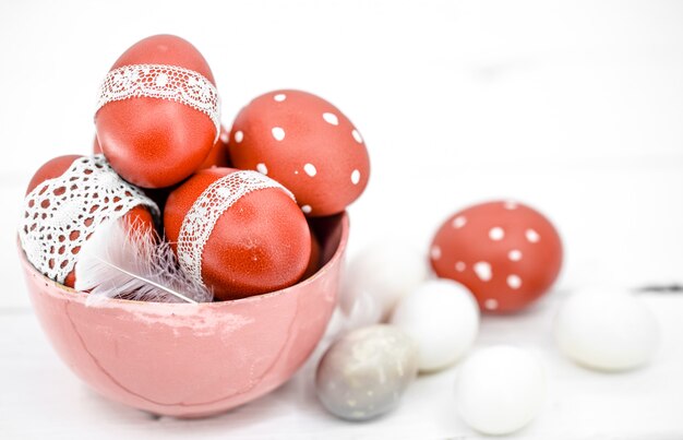 Huevos de Pascua rojos sobre cinta blanca de encaje atado, close-up