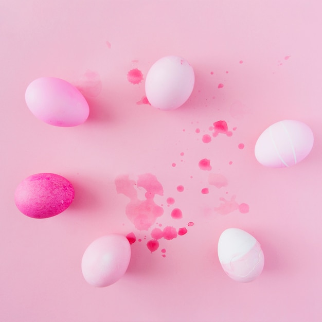 Huevos de Pascua rosa y blanco entre salpicaduras de tinte líquido.
