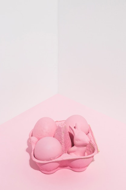 Huevos de Pascua rosa con conejo pequeño en rack