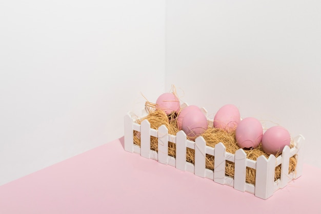 Huevos de Pascua rosa en heno en mesa de luz