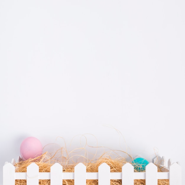 Huevos de Pascua rosados y azules entre heno en caja