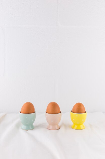 Huevos de Pascua en tazas en textil ligero.