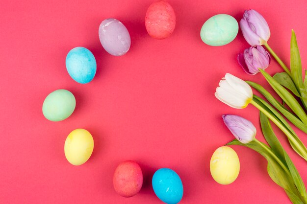 Huevos de Pascua con tulipanes en mesa roja