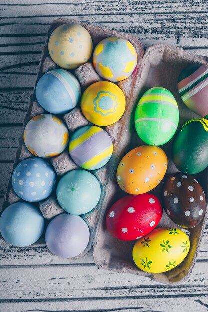 Huevos de Pascua de la vista superior en cartón de huevos en fondo de madera claro.