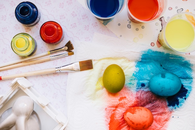 Foto gratuita huevos y pinturas de colores en la mesa