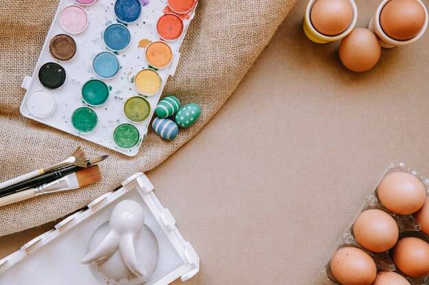 Huevos y pinturas en la mesa con lienzo