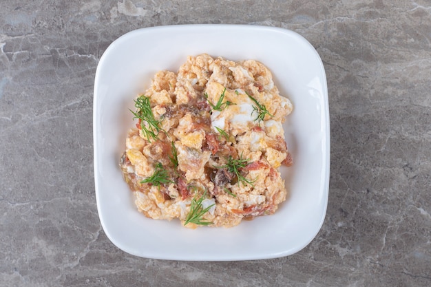 Huevos revueltos con diversas verduras en un tazón blanco.