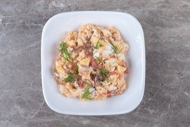 Huevos revueltos con diversas verduras en un tazón blanco.