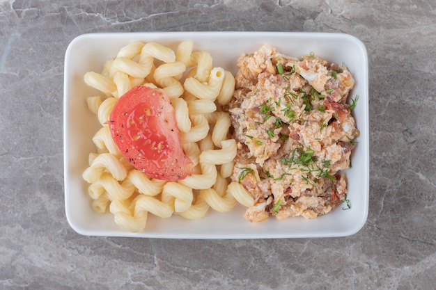 Huevos revueltos y pastas en un plato blanco.