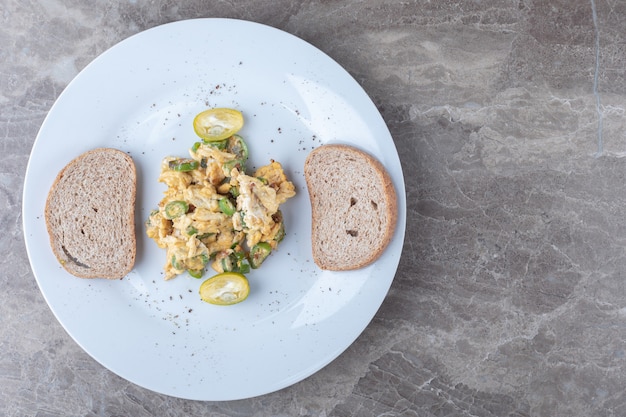 Huevos revueltos y rebanadas de pan en un plato blanco.