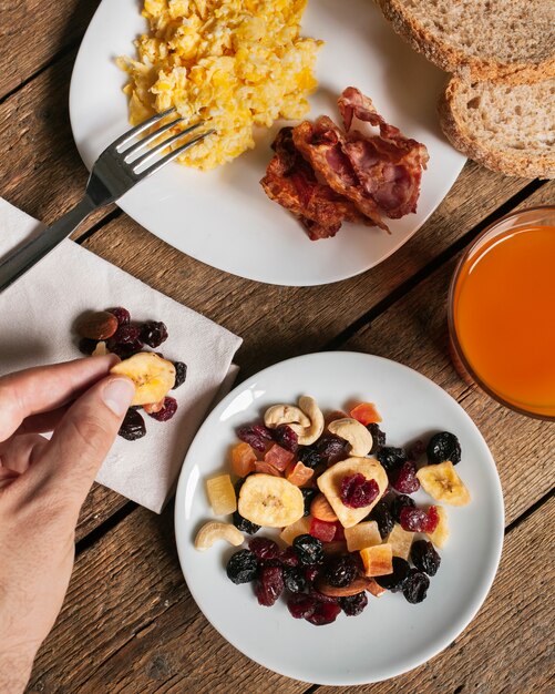 Huevos revueltos con tocino, jugo de naranja y frutas secas