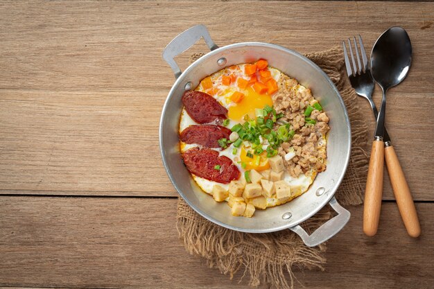 Huevos de sartén espolvoreados con salchicha china, tocino cortado en cubitos, desayuno.