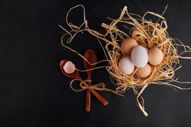 Huevos sobre pasto seco en espacio negro.