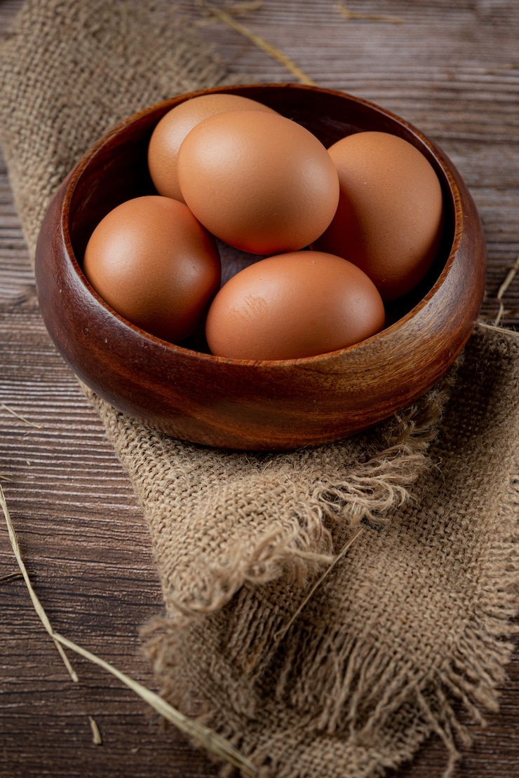 Foto gratuito huevos en tazas sobre arpillera con pasto seco.