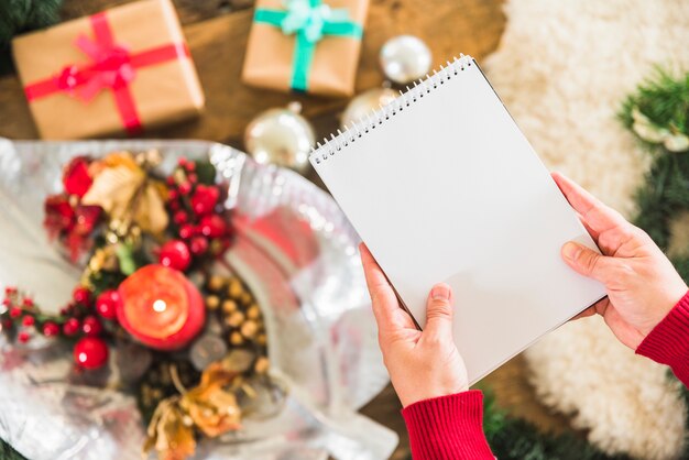 Humano con libreta cerca de mesa decorada para navidad.