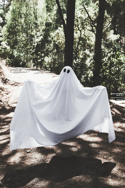 Humano en ropa fantasma levitando por encima de la pasarela en el bosque