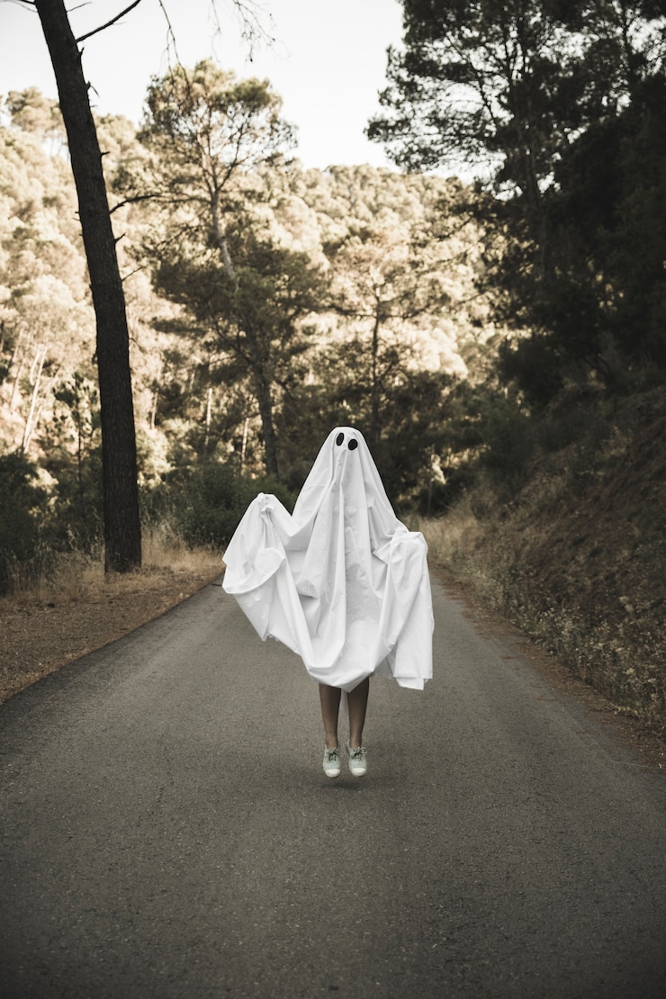 Foto gratuito humano en traje fantasma saltando en la ruta del campo