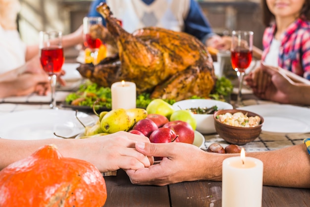 Humanos tomados de la mano en la mesa con la comida