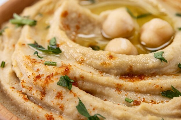 Hummus de garbanzos en un cuenco de madera adornado con pimentón de perejil y aceite de oliva