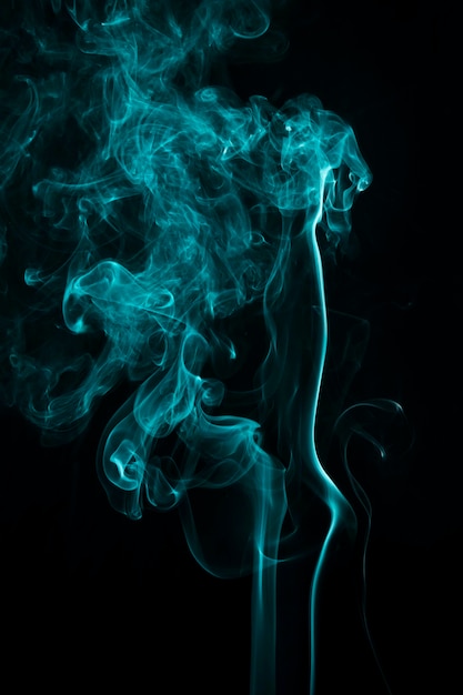 Humo azul abstracto que remolina contra un fondo negro