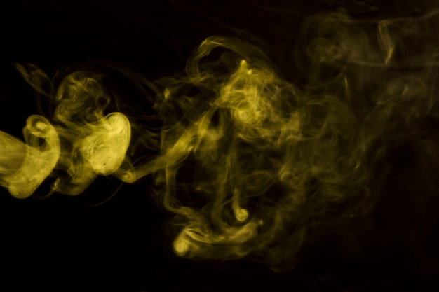 Humo que sopla amarillo abstracto en fondo negro