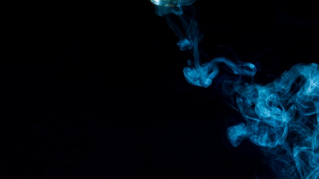 Humo de vapor azul extendido contra el fondo negro