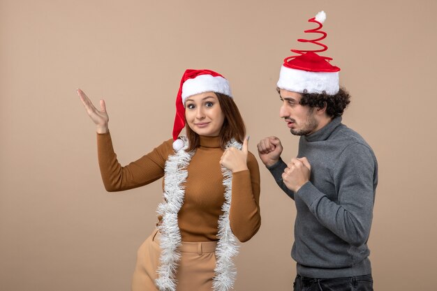 humor navideño con una pareja encantadora fresca emocionada con sombreros rojos de santa claus apuntando arriba