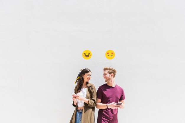 Icono sonriente sobre sonriente pareja joven con smartphone