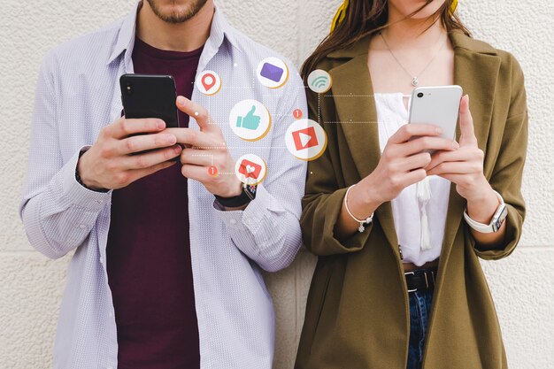 Iconos de notificación móvil entre hombre y mujer usando teléfono celular