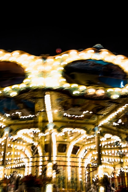 La iluminación borrosa del carrusel gira en el parque de diversiones en la noche