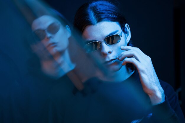 Iluminación de color azul. Retrato de hermanos gemelos. Foto de estudio en estudio oscuro con neón