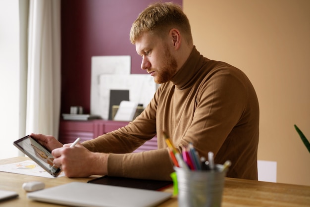 Ilustrador masculino adulto que trabaja en un dispositivo de tableta